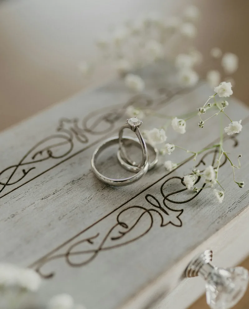 Two wedding rings resting on a carved wooden box beside sprigs of baby’s breath